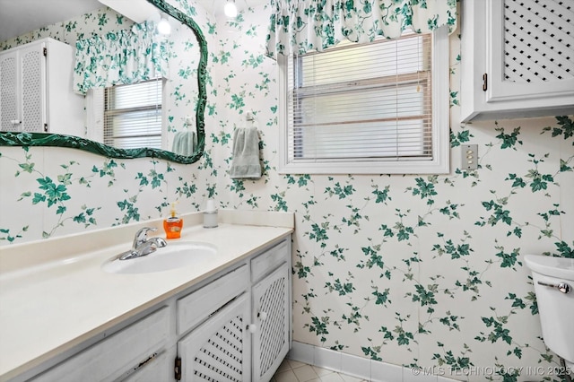 bathroom featuring wallpapered walls, baseboards, toilet, tile patterned floors, and vanity