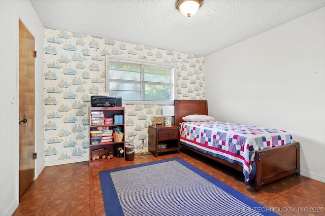 bedroom featuring wallpapered walls, baseboards, and a textured ceiling