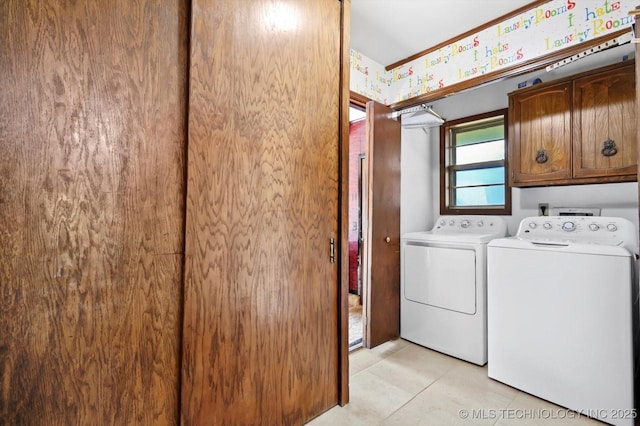 clothes washing area with light tile patterned floors, separate washer and dryer, and cabinet space