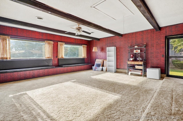 unfurnished living room with plenty of natural light, attic access, visible vents, beamed ceiling, and carpet flooring