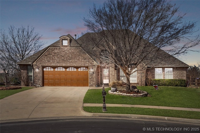 french country home with concrete driveway, a garage, a lawn, and brick siding