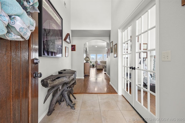 foyer featuring light tile patterned floors, baseboards, and arched walkways