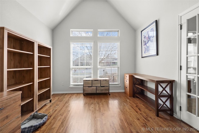 unfurnished room with high vaulted ceiling, baseboards, and wood finished floors