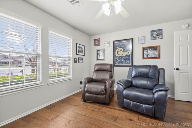 living area featuring visible vents, a ceiling fan, baseboards, and wood-type flooring