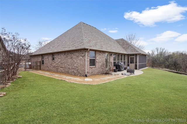 back of property featuring a patio, a yard, a sunroom, and a shingled roof