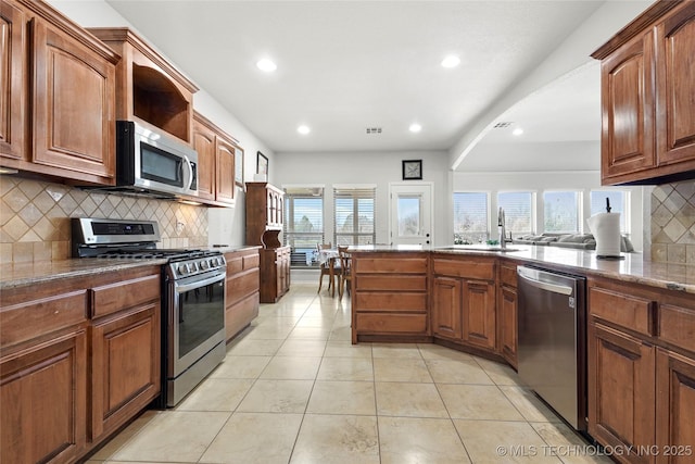 kitchen featuring light tile patterned floors, visible vents, stone counters, a sink, and stainless steel appliances