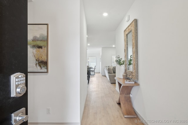 hallway featuring baseboards, light wood-type flooring, and recessed lighting