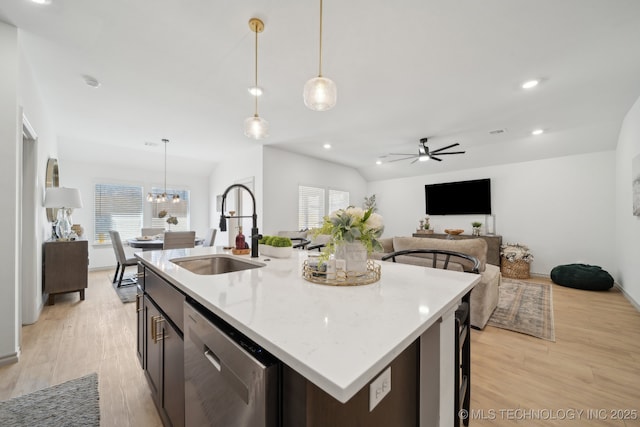 kitchen with light wood finished floors, stainless steel dishwasher, a sink, and a healthy amount of sunlight