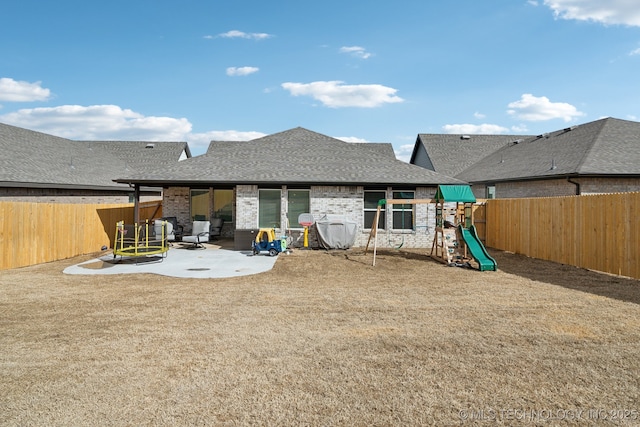 rear view of property with a patio, a shingled roof, a fenced backyard, and brick siding