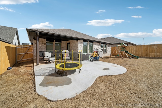 rear view of property featuring brick siding, a patio, a fenced backyard, and a playground