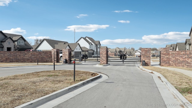 view of road with curbs, a gated entry, a gate, and a residential view