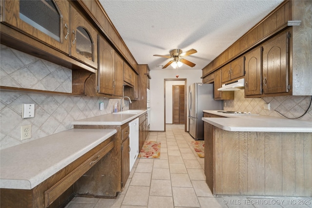 kitchen featuring a ceiling fan, under cabinet range hood, a sink, white appliances, and light countertops