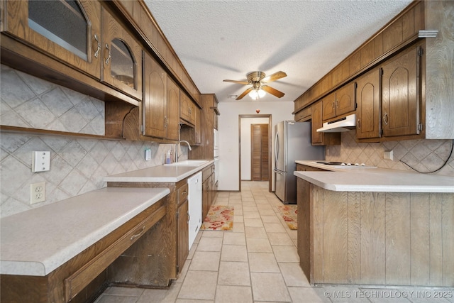 kitchen featuring white appliances, a ceiling fan, a sink, light countertops, and under cabinet range hood