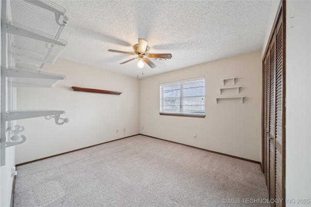 unfurnished room with carpet, a ceiling fan, baseboards, and a textured ceiling