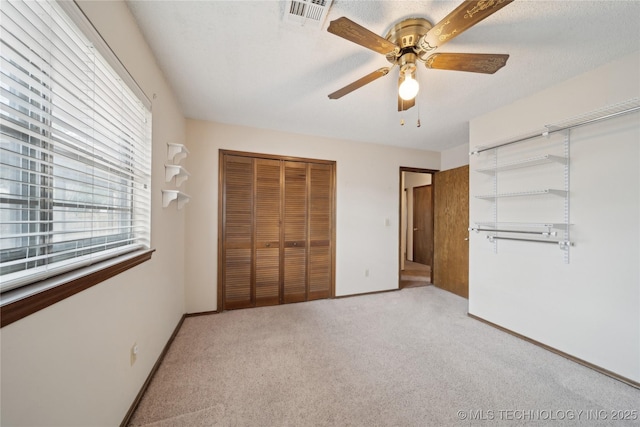 unfurnished bedroom featuring light colored carpet, baseboards, visible vents, and a textured ceiling