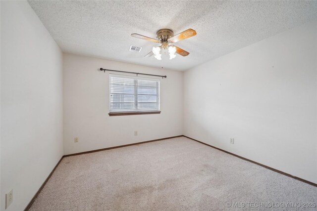 spare room featuring a ceiling fan, visible vents, carpet floors, and a textured ceiling