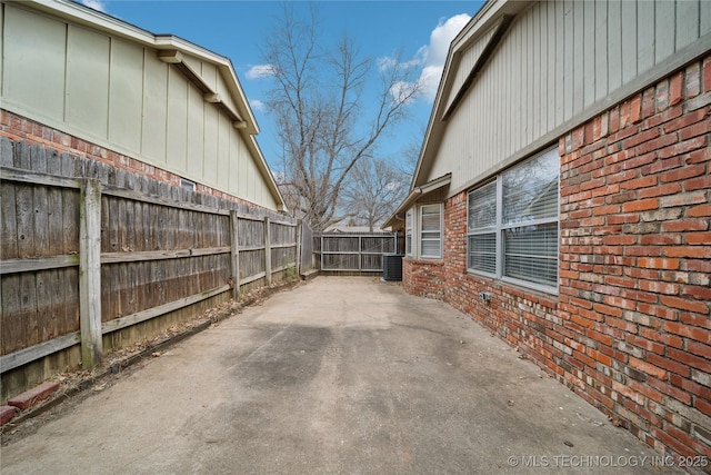 view of patio / terrace with cooling unit, driveway, and fence