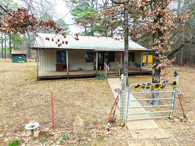 view of front of house with metal roof, a porch, board and batten siding, and an outdoor structure