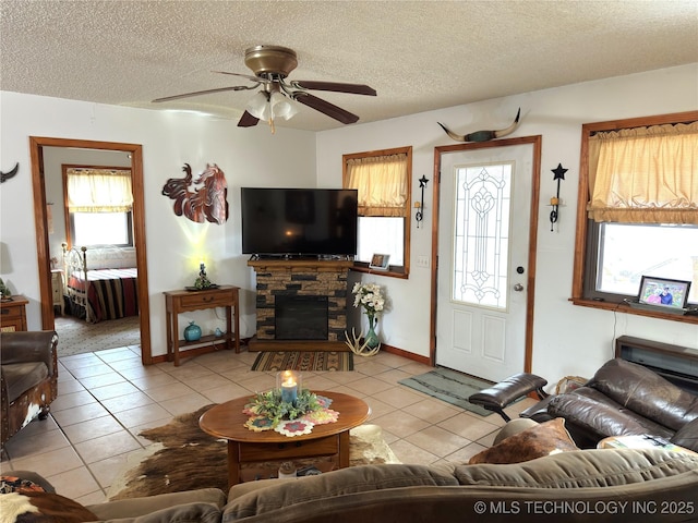 living room featuring a fireplace, a ceiling fan, a textured ceiling, and light tile patterned flooring