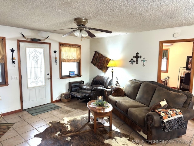 living area featuring a textured ceiling, ceiling fan, baseboards, and tile patterned floors