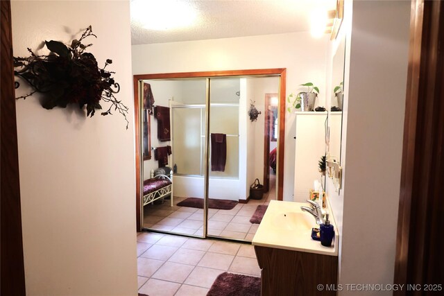 full bathroom with a stall shower, vanity, a textured ceiling, and tile patterned floors