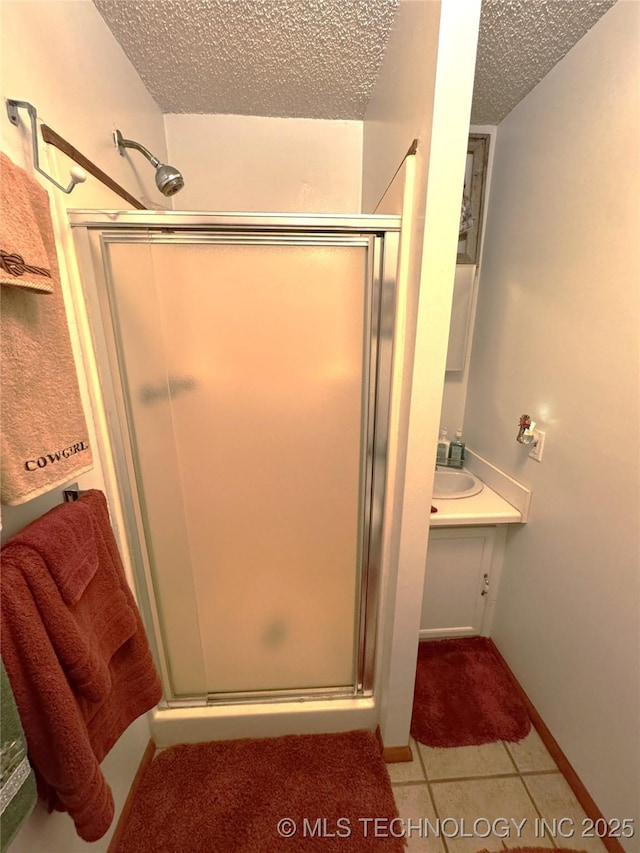 bathroom featuring a stall shower, tile patterned floors, a textured ceiling, and vanity