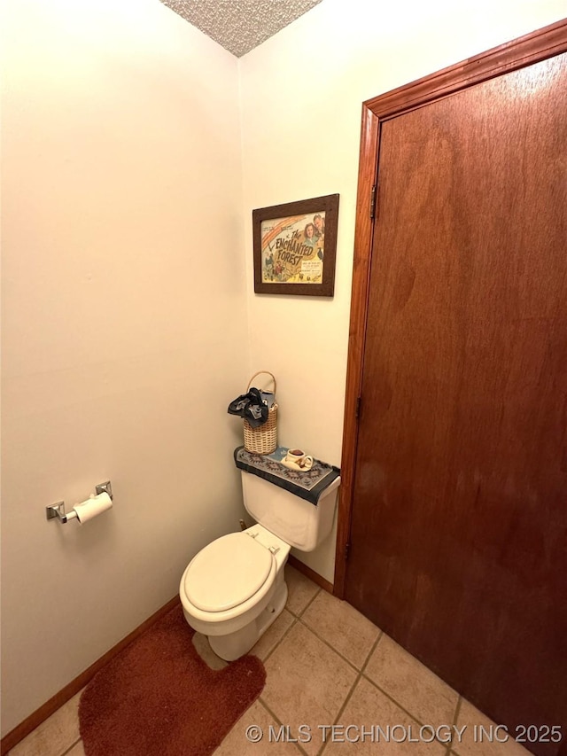 bathroom featuring baseboards, toilet, and tile patterned floors