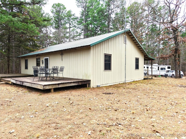 rear view of house featuring metal roof and a wooden deck