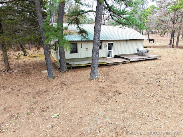 back of property featuring metal roof and a wooden deck