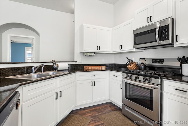 kitchen with a sink, appliances with stainless steel finishes, dark wood finished floors, and white cabinetry