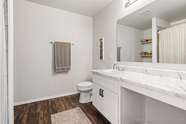 bathroom with vanity, wood finished floors, visible vents, baseboards, and toilet