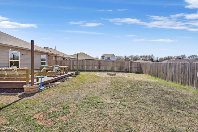 view of yard with a deck, a fenced backyard, and a fire pit