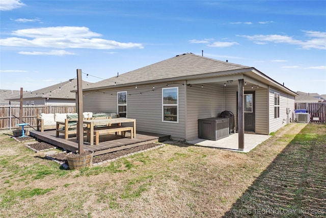 rear view of house with a patio, a fenced backyard, a yard, a shingled roof, and a wooden deck