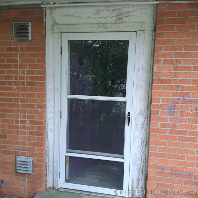 property entrance with brick siding and visible vents