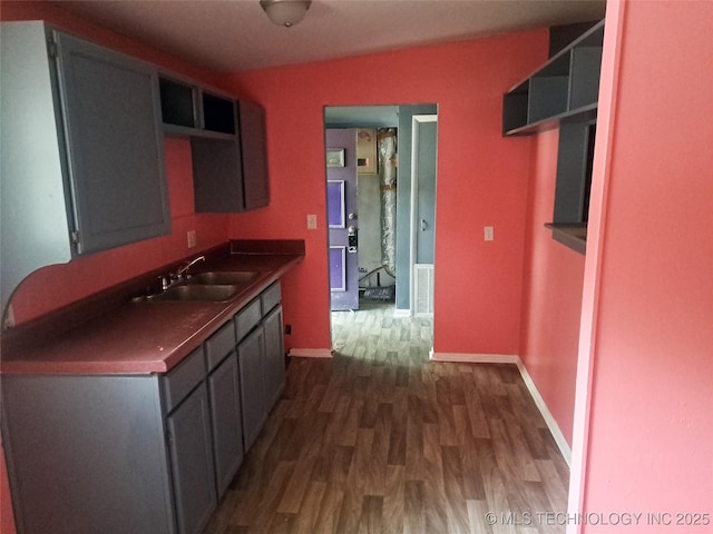 kitchen featuring dark wood-style flooring, a sink, visible vents, baseboards, and open shelves