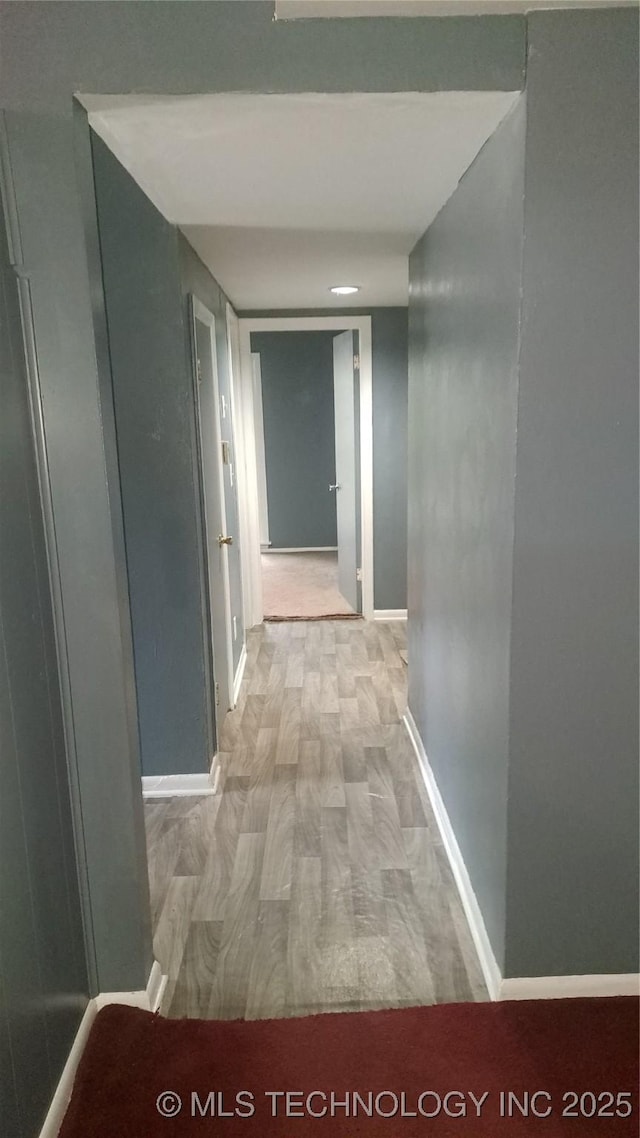 hallway with light wood-type flooring and baseboards