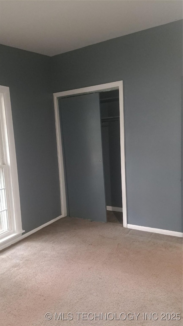 unfurnished bedroom with a closet, baseboards, and carpet flooring