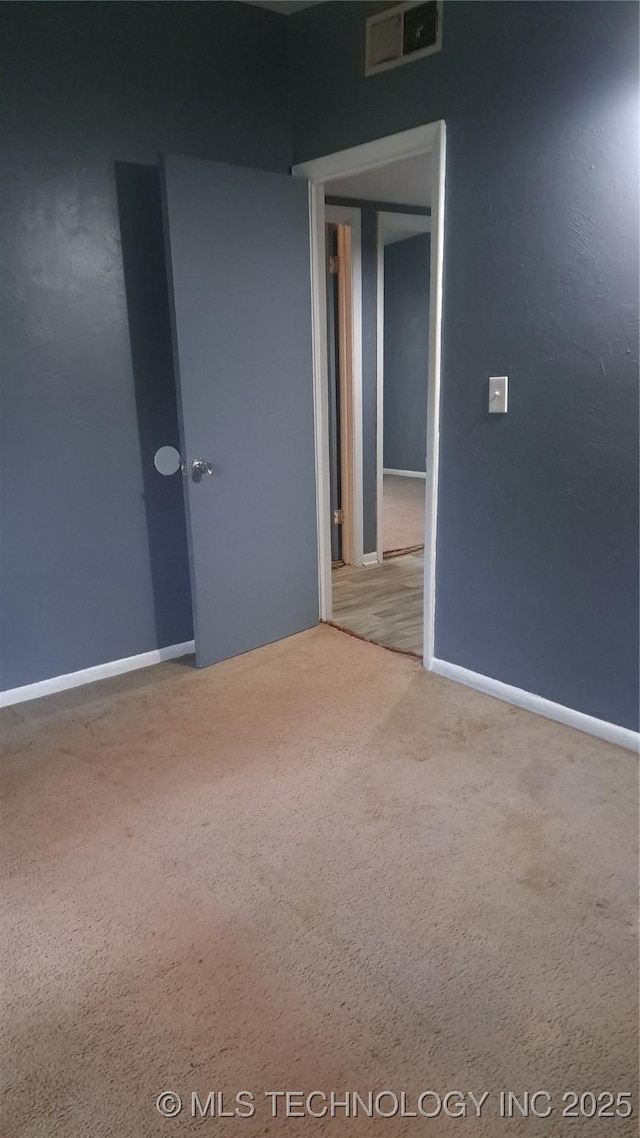 carpeted empty room featuring visible vents and baseboards