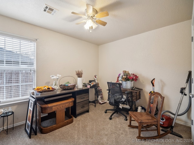 carpeted home office with visible vents, ceiling fan, and a textured ceiling