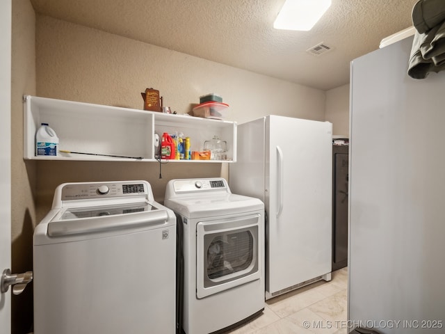 laundry area with a textured ceiling, a textured wall, laundry area, separate washer and dryer, and visible vents