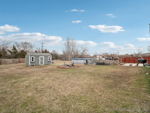 view of yard featuring a fenced backyard, an outdoor structure, a deck, and a shed