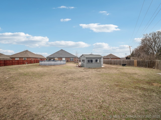 view of yard with a storage unit, an outdoor structure, a fenced backyard, and a fenced in pool