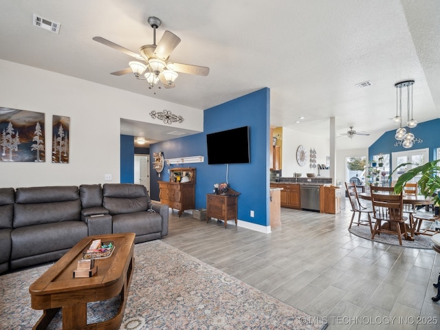 living area with baseboards, light wood-style flooring, visible vents, and a ceiling fan