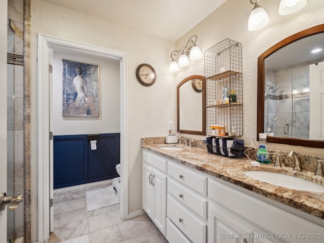 full bath featuring a textured wall, a stall shower, a sink, and toilet