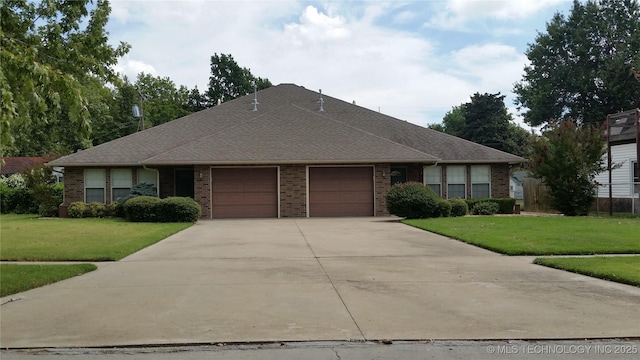 view of front facade featuring an attached garage, driveway, a front lawn, and brick siding