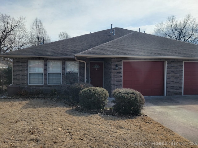 ranch-style house with a garage, driveway, brick siding, and roof with shingles