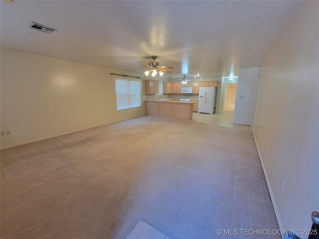 unfurnished living room with light carpet, baseboards, visible vents, and a ceiling fan