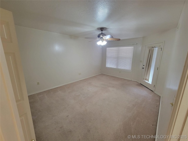 empty room with a ceiling fan, light carpet, and baseboards