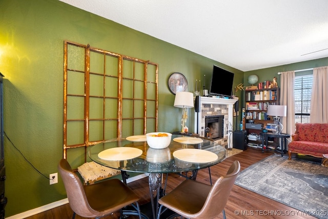 sitting room with a tiled fireplace, baseboards, and wood finished floors