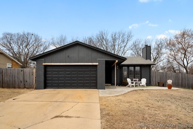 view of front of home with a garage, concrete driveway, brick siding, and fence